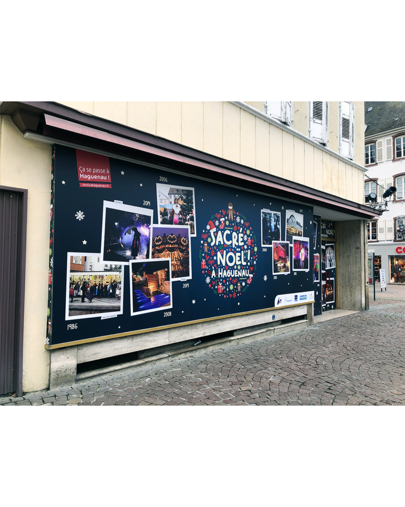 Vitrine décorée et immersive pour l'événement "Sacré Noël ! à Haguenau", illustrant des photos d'archives et une ambiance festive.